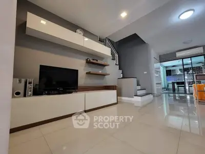 Modern living room with sleek design and open layout, featuring a stylish staircase and contemporary decor.
