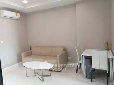 Modern living room with beige sofa, air conditioning, and sleek dining area.