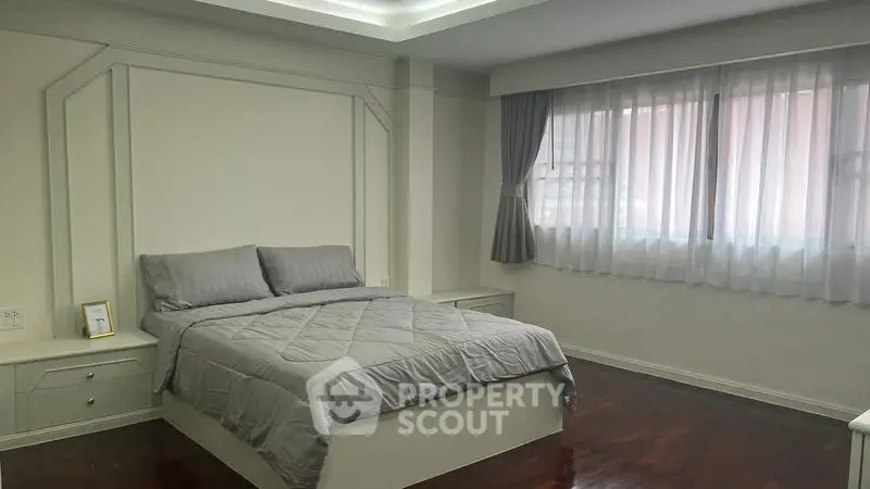Spacious bedroom with elegant decor and large window for natural light.