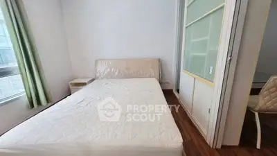 Spacious bedroom with large window and modern furnishings in a stylish apartment.