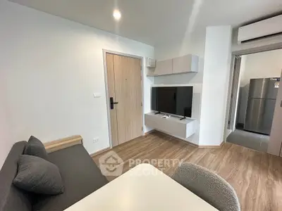 Modern living room with sleek furniture and open kitchen view, featuring a stylish TV setup and air conditioning.