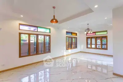Spacious living room with colorful windows and elegant lighting fixtures.