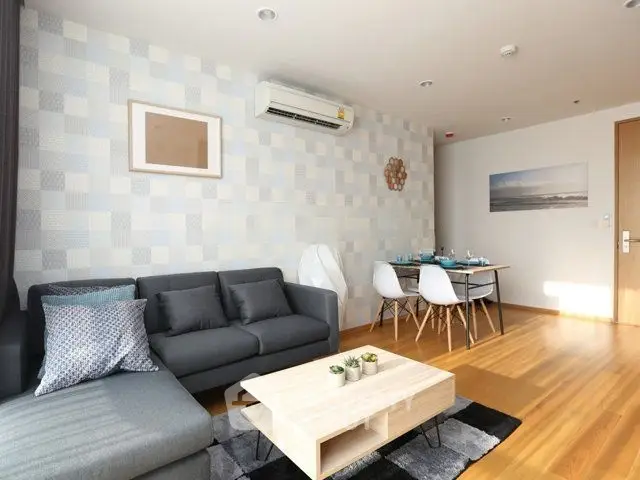 Modern living room with stylish furniture and dining area, featuring wooden flooring and elegant decor.