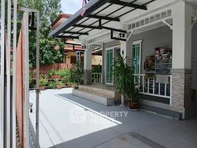 Charming residential entrance with spacious driveway and lush greenery.