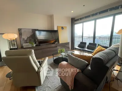 Spacious living room with modern decor and large windows offering city views.
