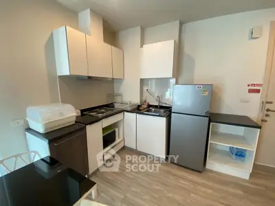 Modern kitchen with sleek cabinets and compact fridge in stylish apartment.