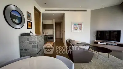 Modern living room with stylish decor and open kitchen layout, featuring a cozy seating area and wall-mounted TV.