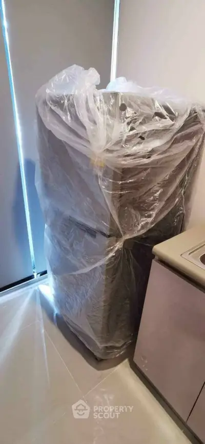 Brand new refrigerator wrapped in plastic in a modern kitchen corner.