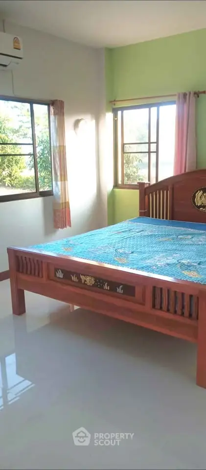 Bright bedroom with wooden bed and large windows offering natural light.