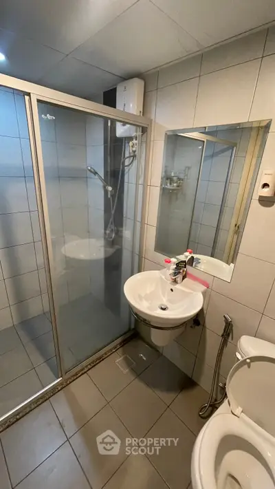 Modern bathroom with glass shower enclosure and sleek fixtures in a contemporary apartment.