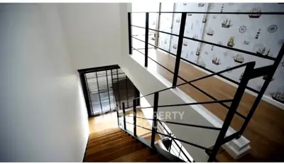 Modern staircase with sleek metal railings and nautical-themed wallpaper