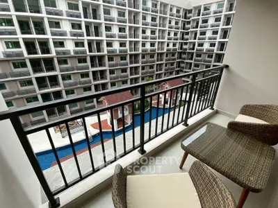 Spacious balcony with a stunning view of modern apartment complex and pool area.