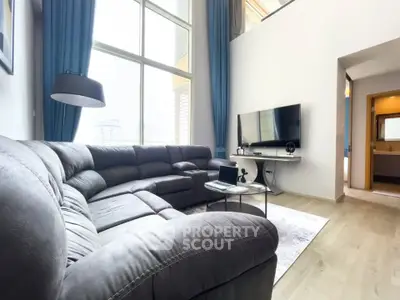 Spacious living room with high ceilings and large windows in modern apartment.