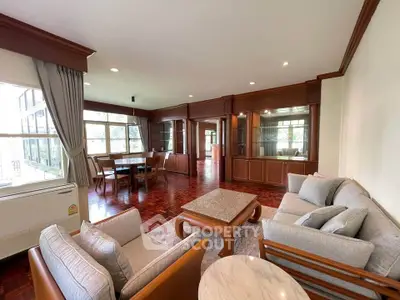 Spacious living room with elegant wooden furniture and large windows offering natural light.