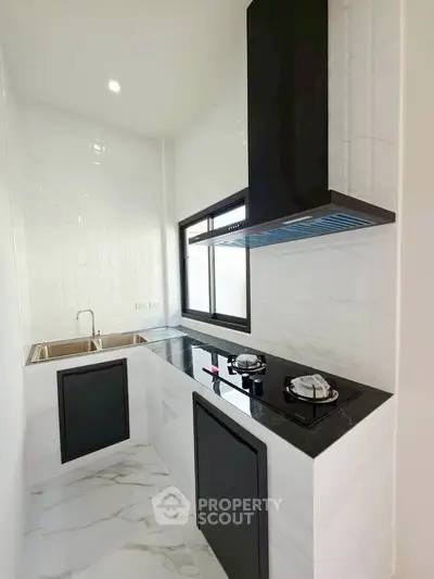 Modern kitchen with sleek black countertops and gas stove in a compact layout.