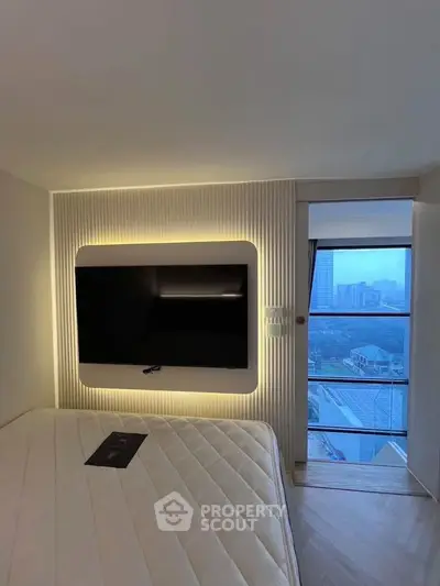 Modern bedroom with wall-mounted TV and large window offering city view.