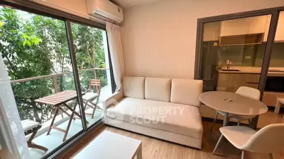 Charming living room with balcony access in modern apartment, featuring cozy seating and natural light.