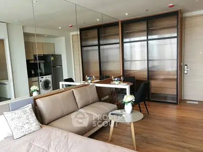 Modern open-plan living room with sleek kitchen and dining area, featuring stylish furniture and appliances.