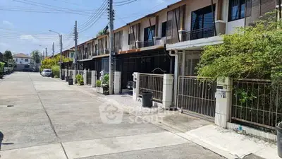 Charming row of modern townhouses with gated entrances and lush greenery in a serene neighborhood.