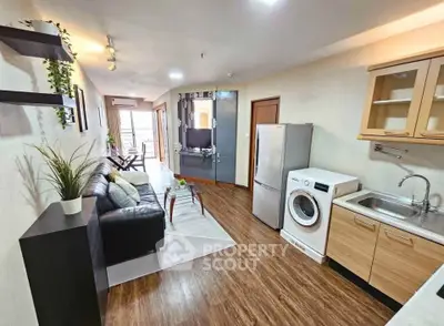 Modern open-plan living room with kitchen, featuring sleek furniture and appliances, ideal for urban living.