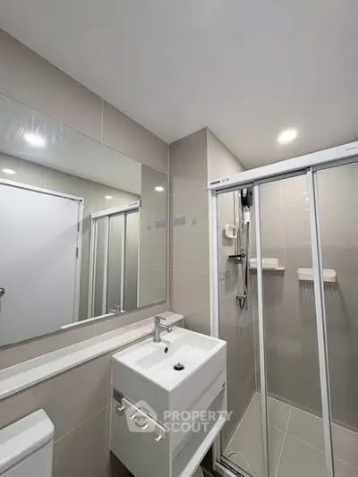 Modern bathroom with sleek shower and elegant vanity in contemporary apartment.