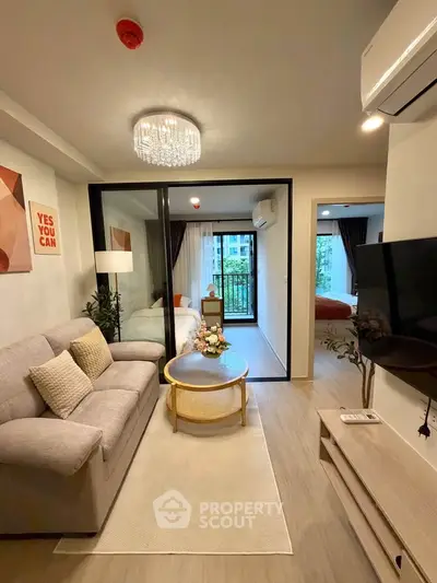 Modern living room with cozy sofa, stylish decor, and glass partition leading to bedroom.