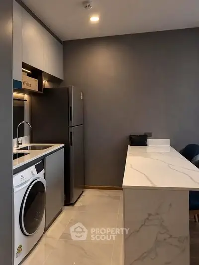Modern kitchen with sleek appliances and marble countertop in a stylish apartment.