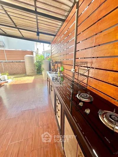 Spacious outdoor kitchen with modern gas stove and wooden paneling