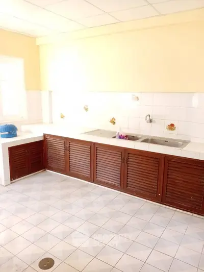 Spacious kitchen with wooden cabinets and dual sink in bright natural light.