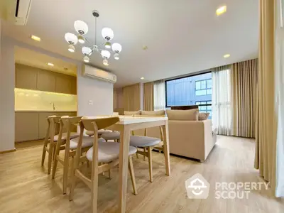 Modern open-plan living room with dining area and large windows in a stylish apartment.