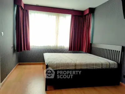 Spacious bedroom with large window and elegant curtains