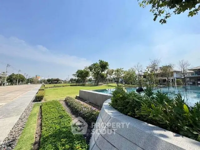Luxurious residential garden with pool and lush greenery under clear blue sky.