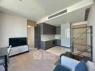 Modern living room with open kitchen, sleek furniture, and natural light.