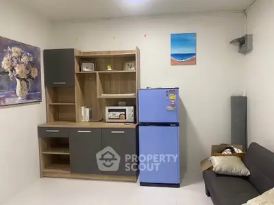 Cozy living space with modern cabinetry, blue fridge, and comfortable seating, perfect for urban living.