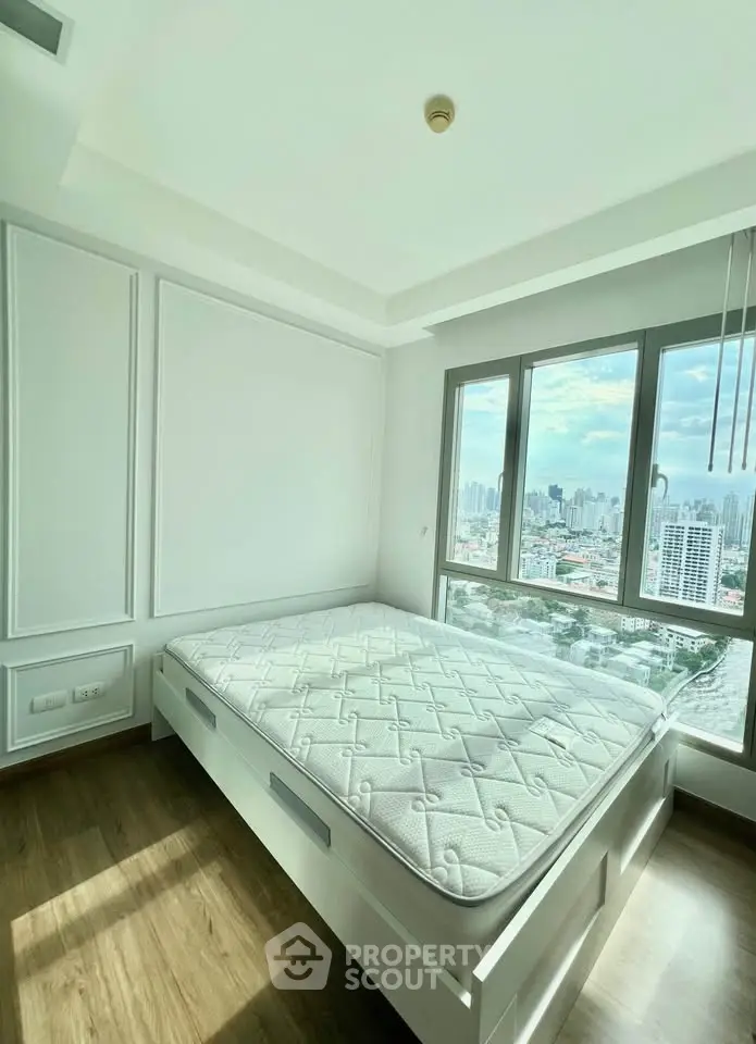 Bright bedroom with large window offering stunning city views, featuring a comfortable bed and modern design.
