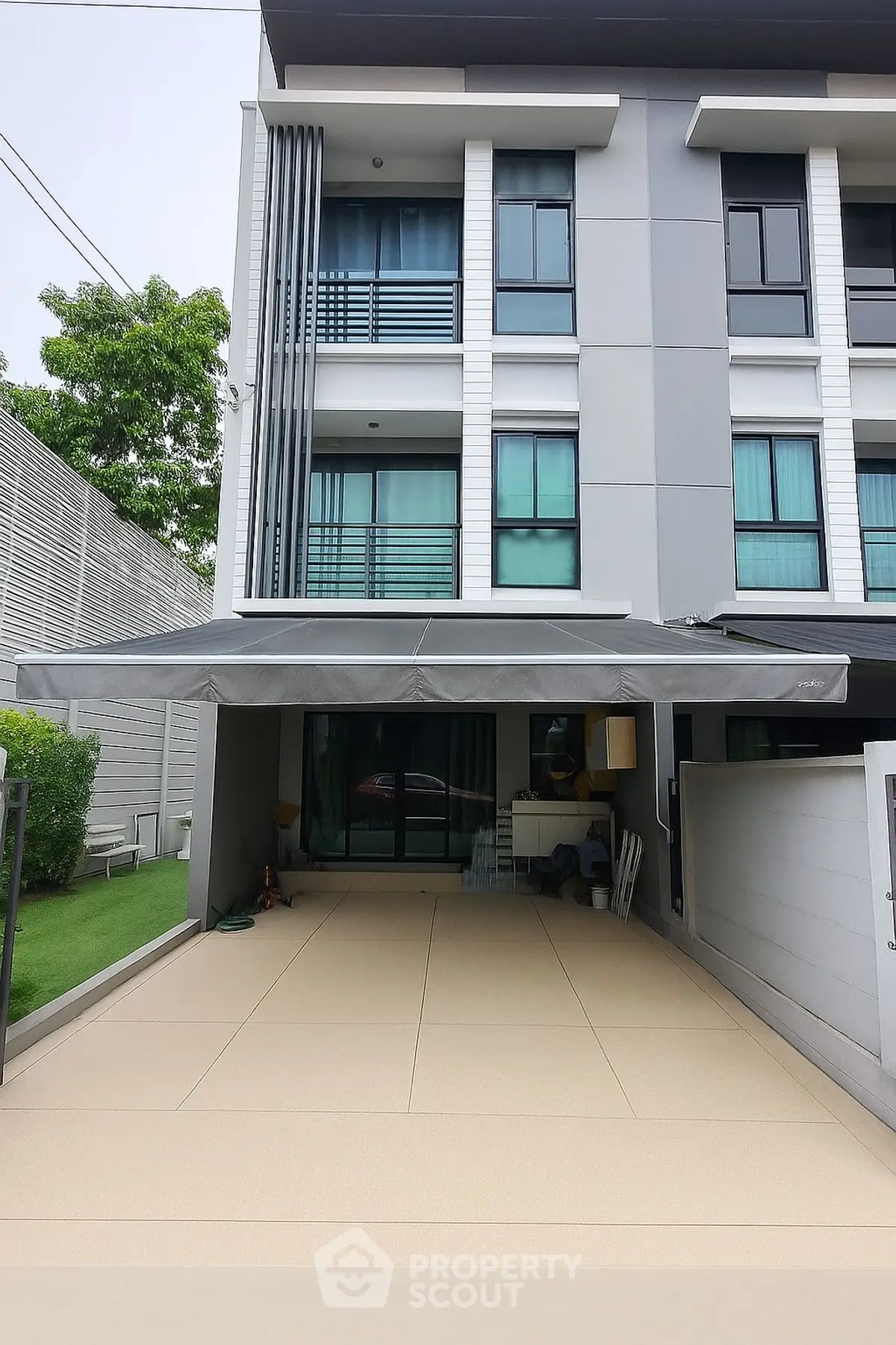 Modern multi-story residential building with spacious driveway and sleek exterior design.