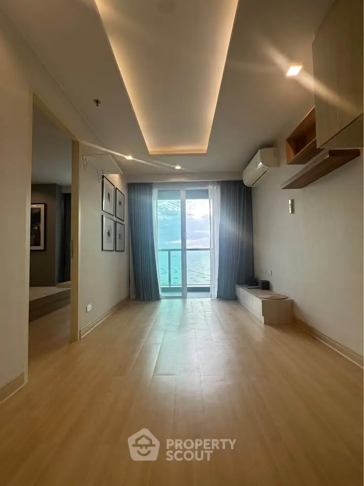 Spacious living room with ocean view and modern design, featuring wooden flooring and elegant ceiling lights.