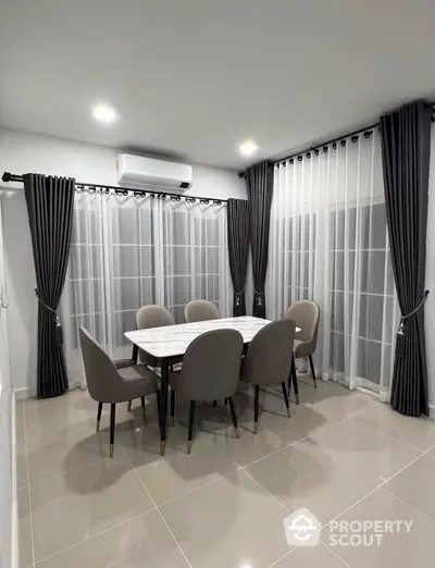 Elegant dining area with modern table and chairs, surrounded by large windows and stylish curtains.