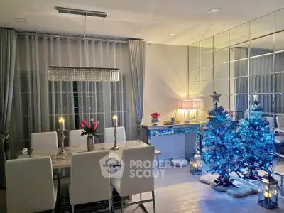 Elegant dining room with festive decor and mirrored wall, featuring a modern chandelier and blue-lit Christmas tree.