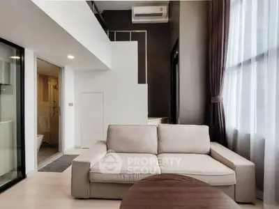Modern living room with beige sofa and large windows in a stylish apartment.