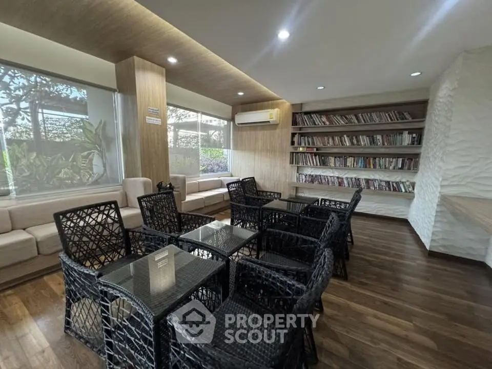 Modern library with stylish seating and extensive book collection in a bright, airy space.