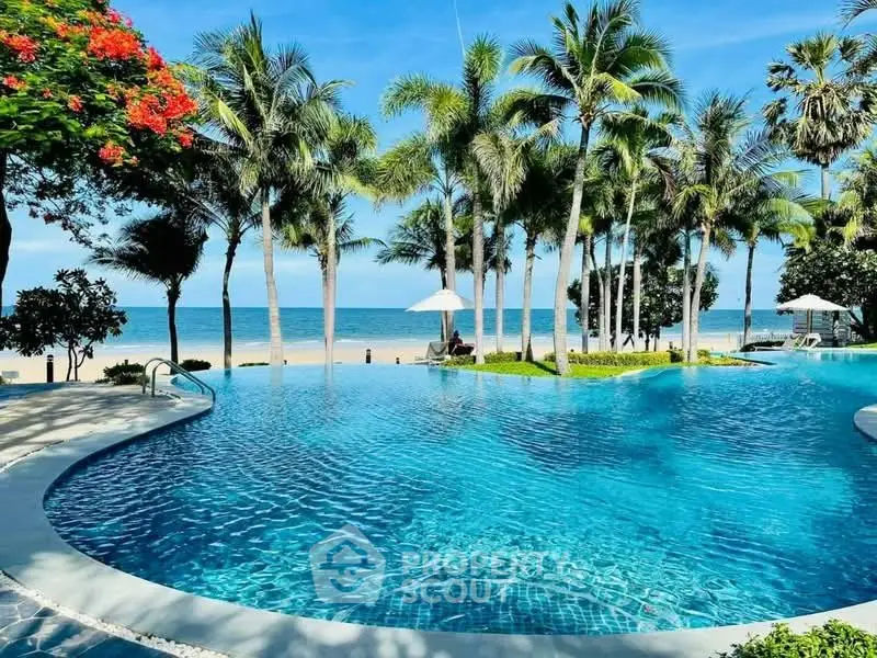 Luxurious beachfront pool with palm trees and ocean view, perfect for relaxation and leisure.