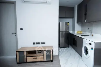 Modern kitchen with sleek appliances and minimalist design, featuring a washing machine and stainless steel fridge.