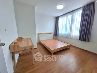 Spacious bedroom with large window allowing ample natural light, hardwood flooring, and a minimalist aesthetic ready for personalization.