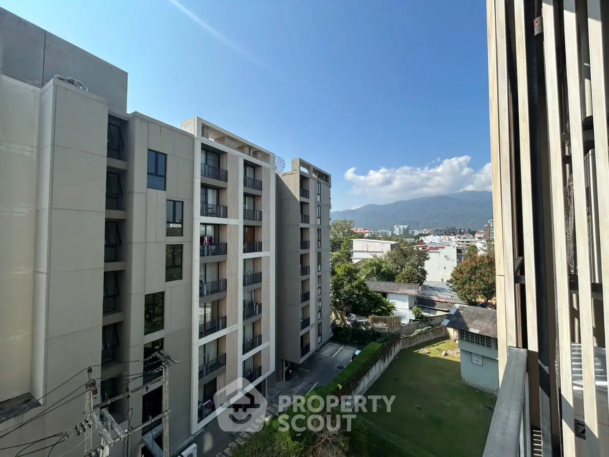 Modern apartment buildings with mountain view and clear blue sky.