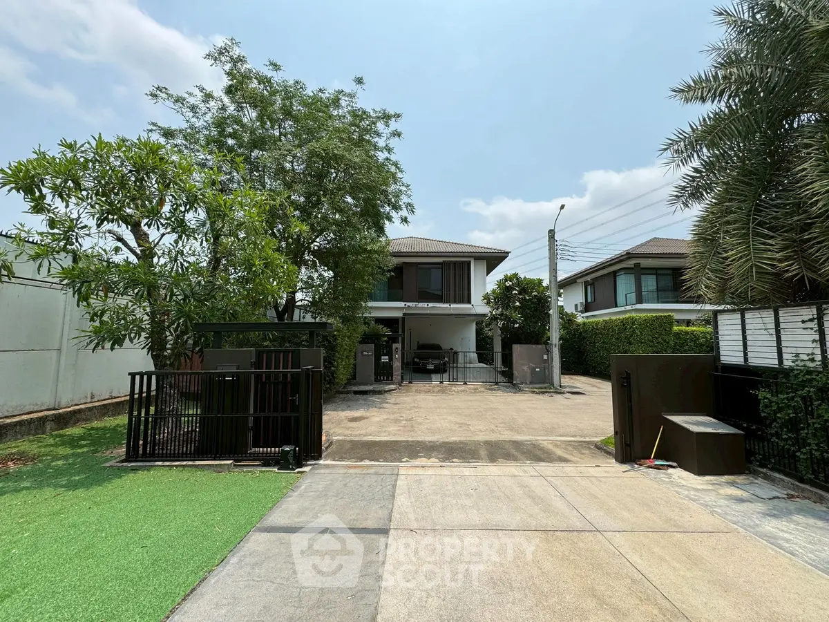 Modern two-story house with spacious driveway and lush greenery, perfect for family living.
