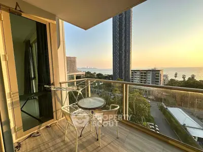 Stunning balcony view with modern high-rise and ocean backdrop at sunset.