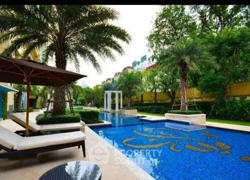 Luxurious outdoor pool area with elegant landscaping and palm trees in a high-end residential complex.