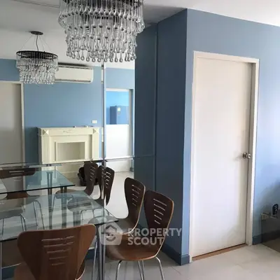 Stylish dining area with modern chandelier and glass table in a cozy apartment.