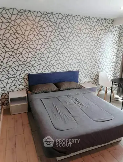 Modern bedroom with stylish geometric accent wall and cozy furnishings.